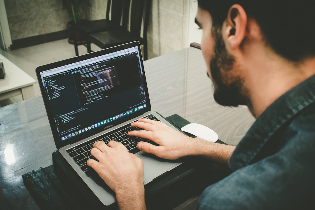 person coding on laptop with futuristic interface
